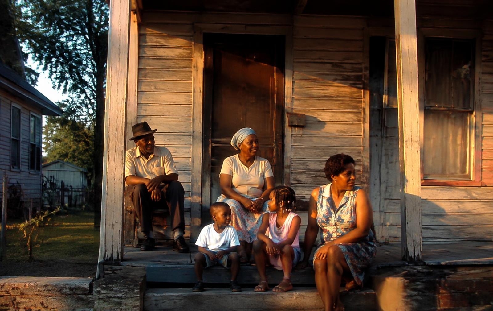 Family gathered on the porch of a historic wooden home